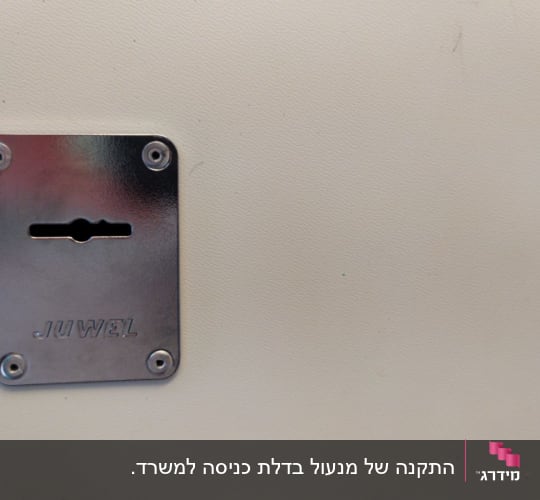 מנעול מתכת עם חריץ מפתח על דלת לבנה